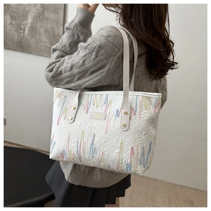 Détail du grand sac cabas rayé avec broderie porté par un mannequin pour la taille