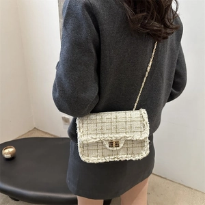 Close-up of woven tweed texture with gold chain strap and metallic twist lock
