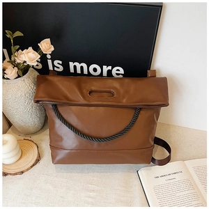 Detail view of brown PU leather tote bag with unique oval handle and twisted rope decor