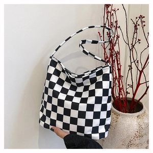 Détail du sac cabas en toile à damier montrant le motif et la bandoulière durable