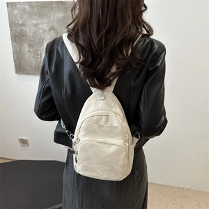 Chic beige mini backpack for women made of textured nylon shown in a stylish street style pose