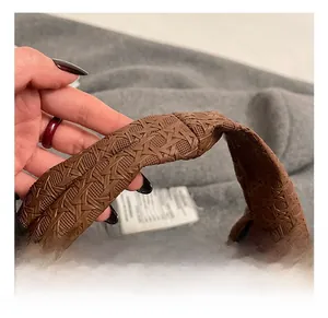 Detail of the thick brown woven texture handle and gold zipper on a chic crescent bag