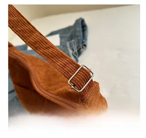 Detail view of the brown corduroy shoulder bag showing silver adjustable metal buckle