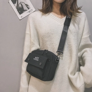 Detail of black canvas crossbody bag with industrial zipper pocket and DCY logo detail