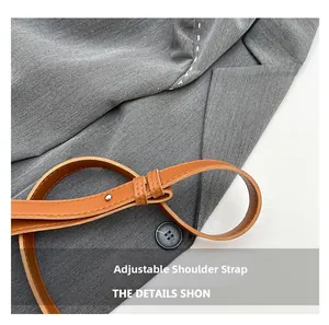 Detail of adjustable brown leather shoulder strap with metallic rivets and white stitching