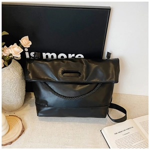 Close-up of black tote bag featuring textured leather and chunky woven rope handles