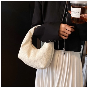 Detail of cream half-moon bag featuring woven texture and integrated handle design