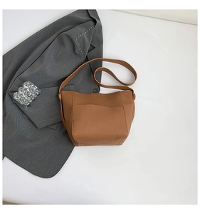 Detail of dark brown lychee leather tote bag with large front pocket and wide strap