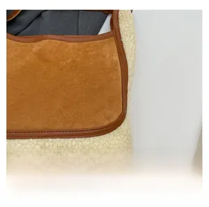 Close-up of brown suede and white fleece patchwork tote bag showing leather piping detail