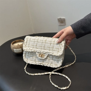 Detailed view of cream tweed texture with gold thread and metallic chain strap