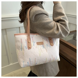 Détail de la broderie ondulée et de l'étiquette en cuir sur un sac cabas élégant