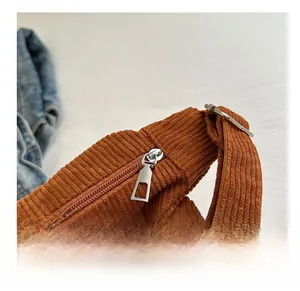 Macro view of corduroy texture and smooth metal zipper on caramel crossbody bag