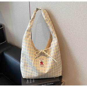 Detail of yellow and blue checkered canvas tote bag with handmade bow and patch