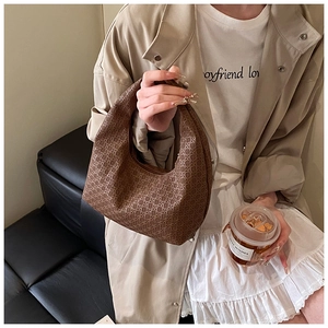 Brown woven hobo bag carried by model in trench coat showing casual daily styling