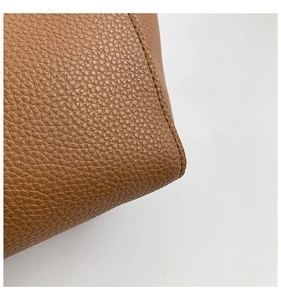 Close-up of brown pebbled leather texture with neat stitching on a minimalist tote bag