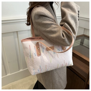 Vue détaillée du sac cabas rayé avec des lanières en cuir rose et des broderies ondulées
