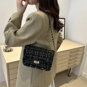 Detailed macro view of woven tweed texture and golden metal chain strap on woman bag