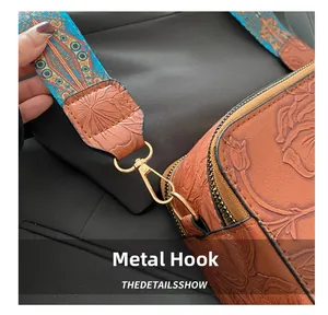 Detail van de gouden metalen haak en blauwe geweven riem op de bruine leren tas