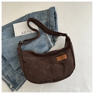 Detail view of dark brown corduroy texture and FASHION leather patch on crescent bag