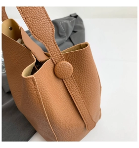 Detail shot of caramel brown litchi grain leather texture and premium edge stitching on tote