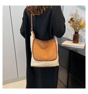 Detail view of brown and cream shearling tote bag with leather piping on a model