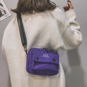 Detail view of the purple canvas crossbody bag with adjustable black nylon shoulder strap