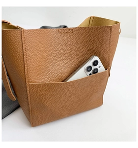 Detailed close-up of brown tote bag's lychee texture and front pocket for smartphone