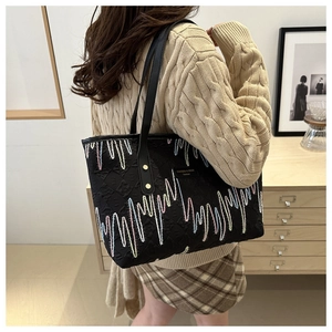 Détail de la broderie en zigzag colorée sur le sac cabas matelassé noir avec anses en cuir