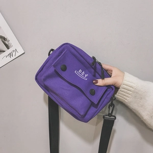 Detail of purple canvas crossbody bag with DCY logo and front pocket with snap button