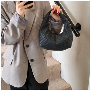 Detailed view of black crescent hobo bag with vintage geometric embossed texture on strap