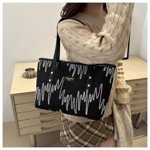 Détail du sac cabas noir avec broderies en zigzag colorées et étiquette en cuir