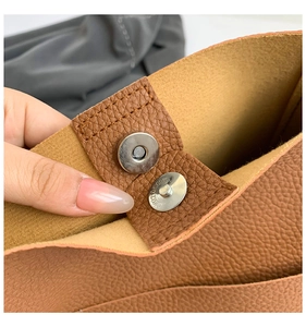 Detail of metal magnetic closure on brown lychee texture leather tote bag