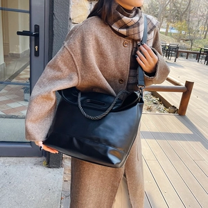Large black faux leather tote bag with braided rope handle and wide crossbody strap