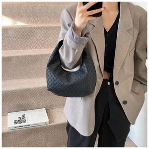 Detail of black crescent handbag featuring dense textured woven patterns in street style