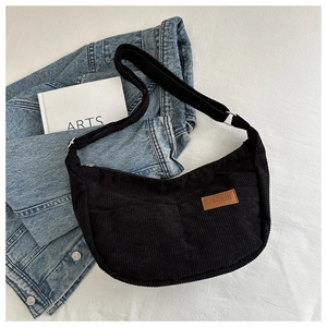 Detail showing black corduroy crescent bag texture with fashion label on white fabric