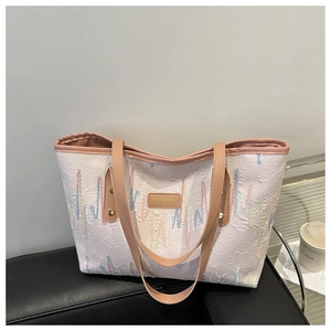 Détail de la broderie ondulée colorée et des anses en cuir sur le sac cabas rayé