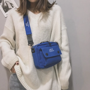 Blue canvas crossbody bag with DČY logo and adjustable wide strap shown on a model
