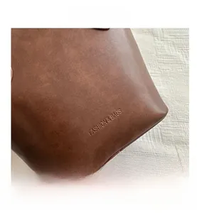 Detail of grain texture and embossed fashion text on brown leather bucket bag