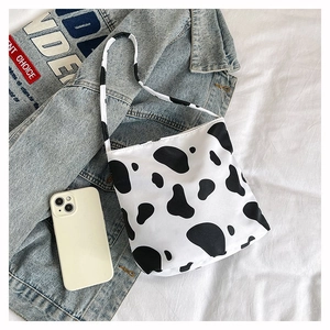 Gros plan détaillé du sac à bandoulière motif vache en toile sur un fond blanc pur