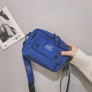 Detailed view of the royal blue canvas crossbody bag with white DCÝ logo and black strap