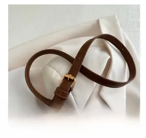 Macro shot of brown leather shoulder strap with gold metal buckle on a white blazer