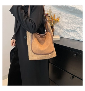 Detail of a brown suede and beige faux shearling tote bag on a black winter coat