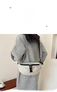 Detail view of a beige minimalist crossbody bag with adjustable black strap and zipper
