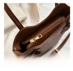 Close-up of smooth gold zipper and stitching details on a brown leather bucket bag