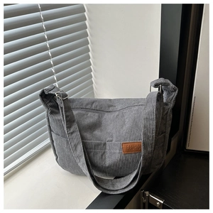 Close-up of grey corduroy tote bag featuring multi-pocket design and FASHION leather tag