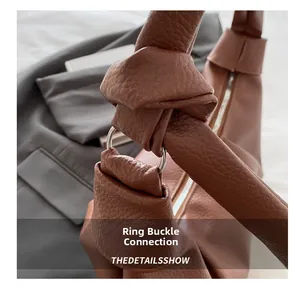 Detail of the knotted handle and metal ring connection on this brown leather handbag