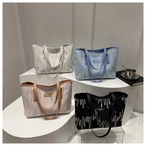 Détail de quatre sacs cabas en tissu rayé blanc, bleu, rose et noir sur présentoir