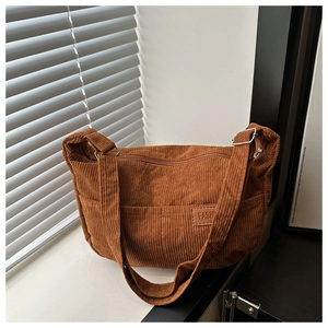 Detailed macro shot of the brown corduroy fabric texture and fashion label on the shoulder bag