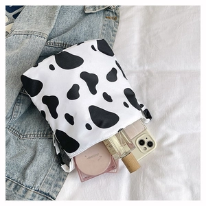 Détail du sac cabas en toile blanche avec motif vache et accessoires du quotidien