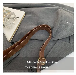 Detail of grey fabric tote with adjustable brown leather strap and gold buckle